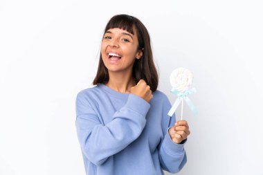 Young mixed race woman holding a lollipop isolated on white background celebrating a victory