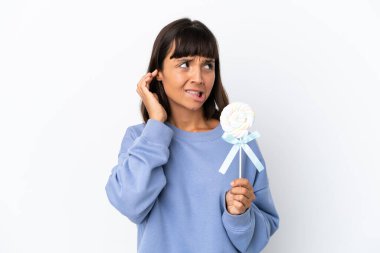 Young mixed race woman holding a lollipop isolated on white background frustrated and covering ears