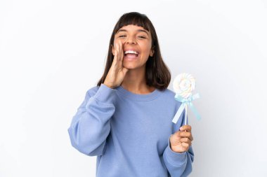 Young mixed race woman holding a lollipop isolated on white background shouting with mouth wide open