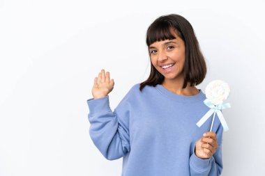 Young mixed race woman holding a lollipop isolated on white background extending hands to the side for inviting to come