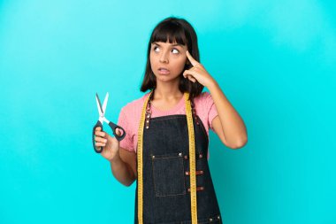 Young mixed race seasmtress woman isolated on blue background having doubts and thinking