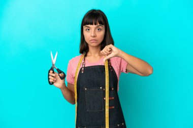 Young mixed race seasmtress woman isolated on blue background showing thumb down with negative expression