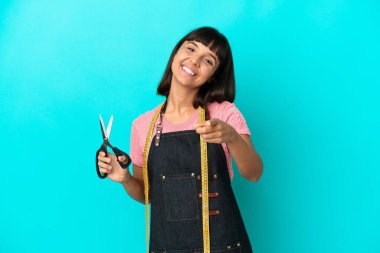 Young mixed race seasmtress woman isolated on blue background pointing front with happy expression