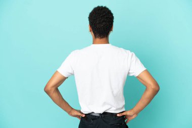 Young African American man isolated on blue background in back position