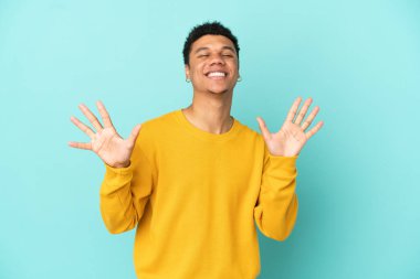 Genç Afrikalı Amerikalı adam mavi arka planda izole edilmiş. Parmaklarıyla ona kadar sayıyor.
