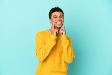 Young African American man isolated on blue background smiling with a happy and pleasant expression