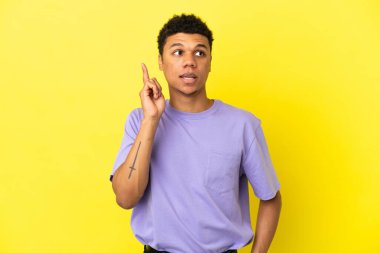 Genç Afrikalı Amerikalı bir adam sarı arka planda izole edilmiş.