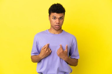 Sarı arka planda izole edilmiş genç Afrikalı Amerikalı bir adam kendini işaret ediyor.