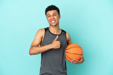 Basketbolcu Afrikalı Amerikalı adam mavi arka planda izole edilmiş bir şekilde baş parmak hareketi yapıyor.