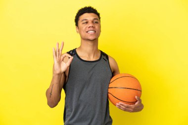 Afrikalı Amerikalı adam sarı arka planda izole edilmiş basketbol oynuyor ve 