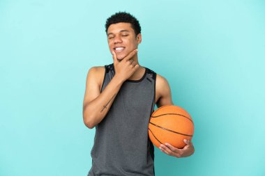 Basketbolcu Afrikalı Amerikalı adam mavi arka planda izole edilmiş mutlu ve gülümsüyor.