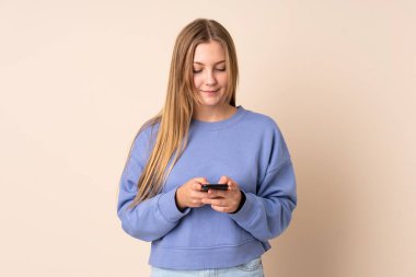 Bej arka planda izole edilmiş genç Ukraynalı kız cep telefonuyla bir mesaj gönderiyor