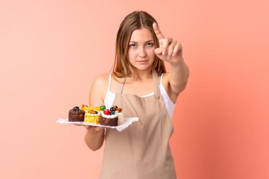 Ukraynalı şefin elinde pembe arkaplanda izole edilmiş bir kek şefinin şeffaf ekrana dokunuşu