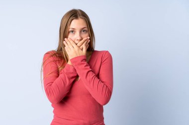 Ukraynalı genç bir kız mavi arka planda izole edilmiş, ağzı elleriyle kapatıyor.