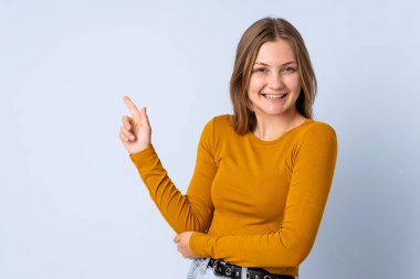 Genç Ukraynalı kız mavi arka planda izole edilmiş, mutlu ve dik duruyor.