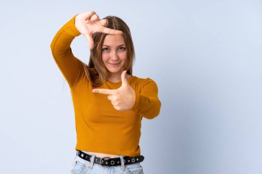 Genç Ukraynalı kız mavi arka planda izole edilmiş, odaklanan yüz. Çerçeve sembolü