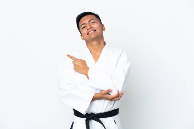 Beyaz arka planda karate yapan genç Ekvadorlu bir adam bir ürün sunmak için kenarı işaret ediyor.