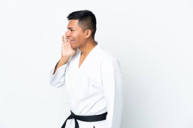 Beyaz arka planda karate yapan genç Ekvadorlu adam ağzı sonuna kadar açık bağırıyor.