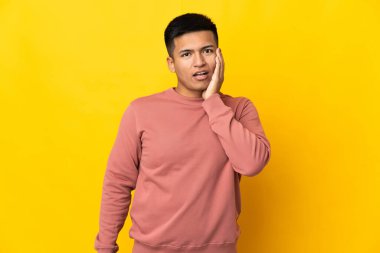 Genç Ekvadorlu adam sarı arka planda izole edilmiş, şaşırmış ve şok olmuş bir yüz ifadesi var.