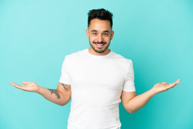 Kafkasyalı genç adam mavi arka planda izole edilmiş ve şok olmuş yüz ifadesi var.