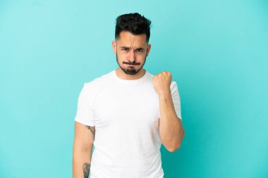 Mutsuz bir ifadeyle mavi arka planda izole edilmiş genç beyaz bir adam.