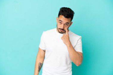 Mavi arka planda izole edilmiş genç beyaz bir adam bir şey gösteriyor.