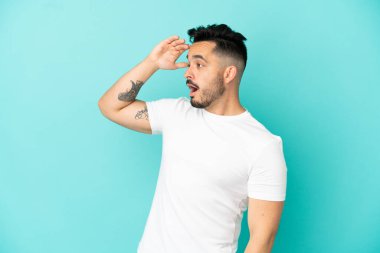 Mavi arka planda mahsur kalmış beyaz bir genç var.