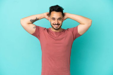 Kafkasyalı genç adam mavi arka planda tek başına gülüyor.