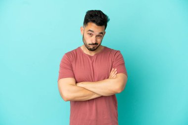 Mutsuz bir ifadeyle mavi arka planda izole edilmiş genç beyaz bir adam.