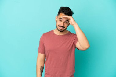 Kafkasyalı genç bir adam mavi arka planda izole edilmiş. Bir şeye bakmak için uzaklara bakıyor.