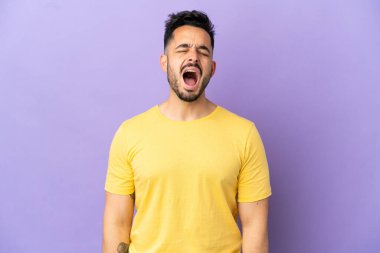 Mor arka planda izole edilmiş genç beyaz adam ağzı açık bir şekilde öne doğru bağırıyor.