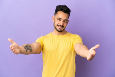 Mor arka planda izole edilmiş genç beyaz adam sunar ve davet eder.