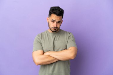 Mutsuz bir ifadeyle mor arka planda izole edilmiş genç beyaz bir adam.