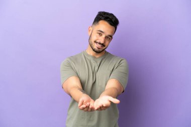 Mor arka planda izole edilmiş genç beyaz bir adam bir ilan vermek için avucunda hayali bir fotokopi makinesi tutuyor.