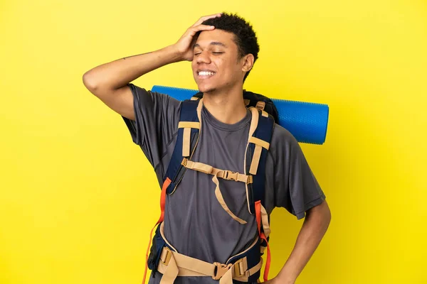 若い登山家アフリカ系アメリカ人男性と大きなバックパックを黄色の背景に多くの笑みを浮かべて隔離 — ストック写真