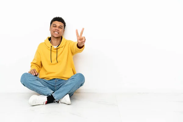 Giovane Uomo Afroamericano Seduto Sul Pavimento Isolato Sfondo Bianco Sorridente — Foto Stock