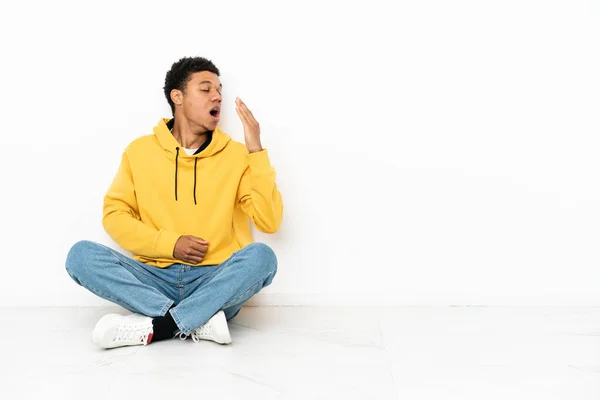 Joven Afroamericano Sentado Suelo Aislado Sobre Fondo Blanco Bostezando Cubriendo —  Fotos de Stock