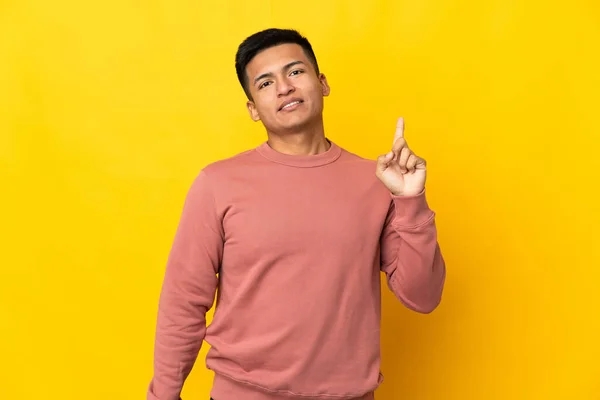 Młody Ekwadorczyk Człowiek Odizolowany Żółtym Tle Pokazując Podnosząc Palec Znak — Zdjęcie stockowe