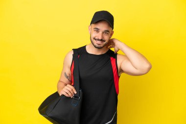 Spor çantalı genç beyaz adam sarı arka planda izole edilmiş gülüyor.