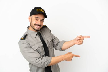 Beyaz arka planda izole edilmiş beyaz tenli genç bir adam parmağını yana uzattı ve bir ürün sundu.