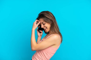 Mavi arka planda izole edilmiş cep telefonu kullanan beyaz bir kadın.