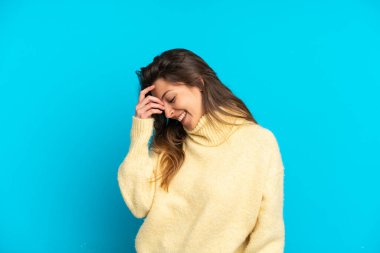 Mavi arka planda izole edilmiş genç beyaz kadın gülüyor.