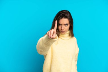 Mavi arka planda izole edilmiş beyaz bir kadın ciddi bir ifadeye sahip birini sayıyor