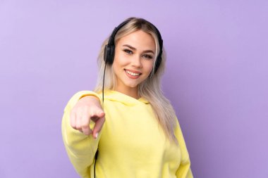 Soyutlanmış mor arka planda müzik dinleyen genç kız.