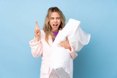 Pijamalı genç Rus kız mavi arka planda izole edilmiş ve şans diliyor.