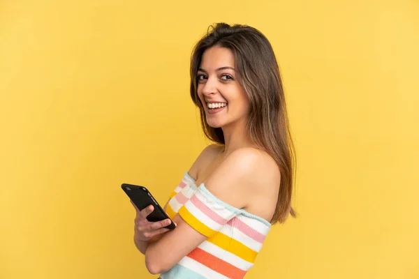 Young Caucasian Woman Isolated Yellow Background Holding Mobile Phone Arms — Zdjęcie stockowe