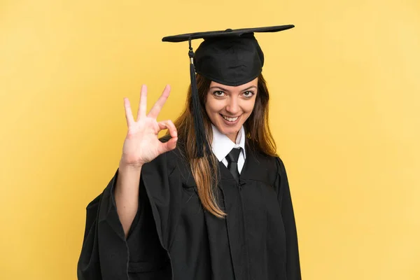 Graduado Universitario Joven Aislado Sobre Fondo Amarillo Mostrando Signo Con —  Fotos de Stock