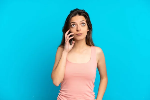 Giovane Donna Caucasica Utilizzando Telefono Cellulare Isolato Sfondo Blu Guardando — Foto Stock