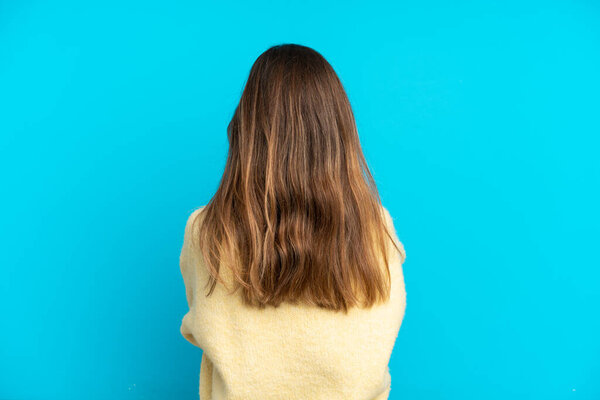 Young caucasian woman isolated on blue background in back position