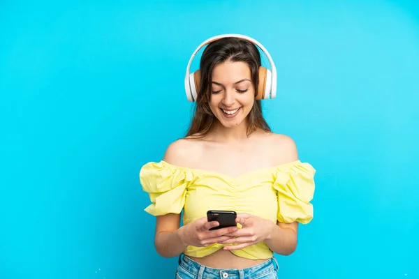 Joven Mujer Caucásica Aislada Sobre Fondo Azul Escuchando Música Mirando —  Fotos de Stock